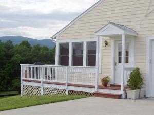 a white house with a porch and a white fence at Fairhill Farm Country Vacation Rentals in Stanardsville