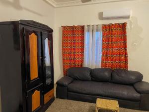 ein Wohnzimmer mit einem schwarzen Ledersofa und einem TV in der Unterkunft Sylvadore'Appart in Cotonou