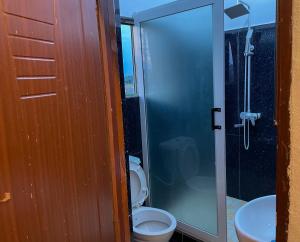 ein Badezimmer mit einem WC und einer Glasduschkabine in der Unterkunft Sylvadore'Appart in Cotonou