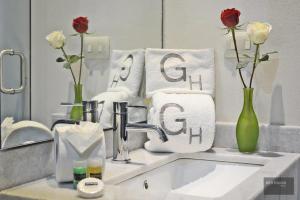 Hotel Gertrudis في موريليا: بالوعة الحمام مع الزهور والمناشف أمام المرآة