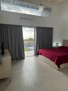 a bedroom with a red bed and a large window at Condo Costa Azul in Costa Azul