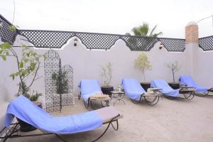 Un grupo de sillas y mesas azules en un patio. en "Kasbah de Jade", Maison d'hôtes avec piscine chauffée, jacuzzi, service hôtelier, exclusivité possible !, en Marrakech