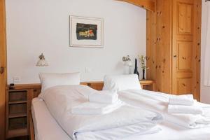een wit bed met witte lakens en kussens erop bij Unterkunft CASA LA RODA NR 5 URSIN in Sedrun