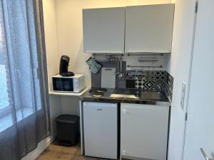 a kitchen with white cabinets and a sink and a microwave at superbe studio meublé avec parking in Maubeuge