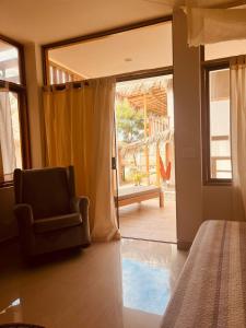um quarto com uma cadeira e uma porta de vidro deslizante em La Nómada Digital - Máncora Playa & Piscina em Máncora