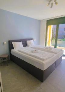 ein großes Bett in einem Schlafzimmer mit Fenster in der Unterkunft Apartment 10 Palmen Locarno in Locarno