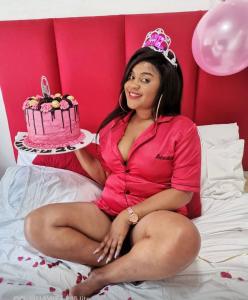 a woman sitting on a bed with a birthday cake at Ouklip Place Hotels in Roodepoort