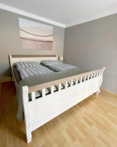 a white bed in a bedroom with a painting on the wall at "Ferienwohnung Naturliebe - grünes Paradies im Zentrum in Luckenwalde +8 photos
