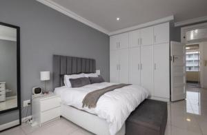een witte slaapkamer met een groot bed en witte kasten bij The Views BNB in Durban