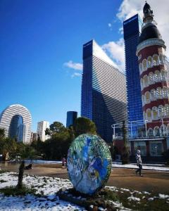 a globe in front of a city with tall buildings at Orbi city - Premium Class Rooms in Batumi