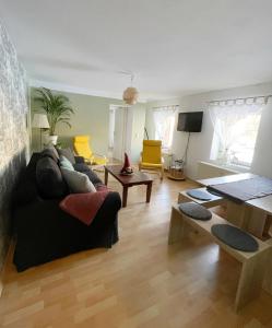 ein Wohnzimmer mit einem schwarzen Sofa und gelben Stühlen in der Unterkunft FeWo Jack's World in Luckenwalde