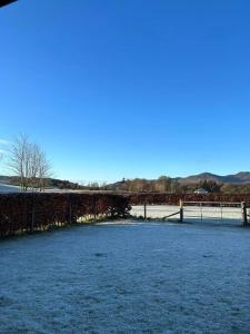 a snow covered field with a bridge and a fence at Fairness Cottage, Near Comrie in Comrie