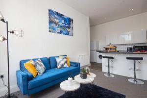 a living room with a blue couch and a kitchen at Stylish 2 Bed Apt in Leeds Centre - FREE Parking! Contact us for Better Offers! in Leeds