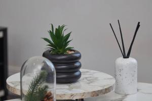 a table with two vases and a plant on it at Stylish 2 Bed Apt in Leeds Centre - FREE Parking! Contact us for Better Offers! in Leeds