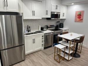 a kitchen with white cabinets and a stainless steel refrigerator at Beautiful 2 Bedroom Guest Suite in Leduc 11 mins to Edmonton Intl Airport, Free Wifi, Netflix ,Cable & Workstation in Leduc