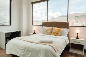 拉巴斯Sky Suites - Stunning Location with a great view of La Paz的一间卧室设有一张大床和两个窗户