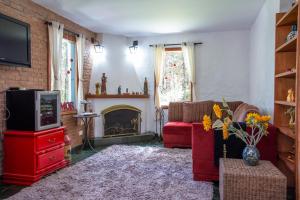 uma sala de estar com um sofá vermelho e uma lareira em Pousada Suiça Mineira Garden em Monte Verde