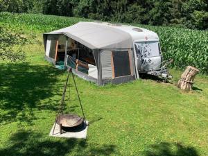 an rv parked in a field with a swing at Familienwohnwagen im Emmental 