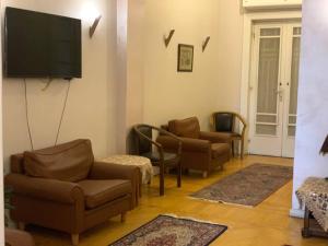 uma sala de estar com cadeiras e uma televisão de ecrã plano em Zamalek Garden villa-Abu El Feda no Cairo