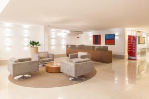 een lobby met stoelen en een tafel en een coke-machine bij Ramada Hotel & Suites Campos Pelinca in Campos dos Goytacazes