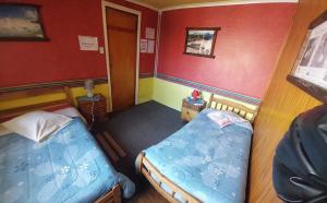 2 camas en una habitación pequeña con paredes rojas en Hospedaje Independencia y camping, en Punta Arenas