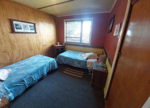 Cette petite chambre comprend 2 lits et une fenêtre. dans l'établissement Hospedaje Independencia y camping, à Punta Arenas