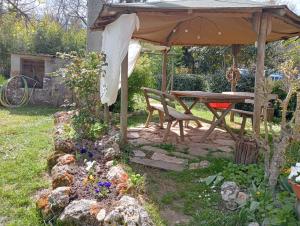 einem Picknicktisch und einer Bank unter einem Sonnenschirm im Garten in der Unterkunft Affittacamere la Casella Monteriggioni in Monteriggioni