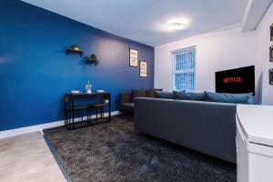 ein Wohnzimmer mit einem Sofa und einer blauen Wand in der Unterkunft Spacious modern apartment in central location - free parking in Liverpool