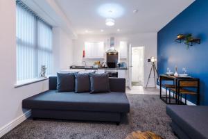 a living room with a blue couch and a kitchen at Spacious modern apartment in central location - free parking in Liverpool