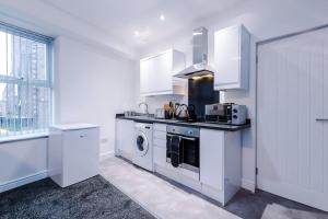 a kitchen with white cabinets and a washer and dryer at Spacious modern apartment in central location - free parking in Liverpool