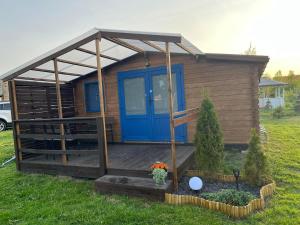 ein winziges Haus mit einer blauen Tür und einer Veranda in der Unterkunft Swojskie Chatki - Marynarska Chatka in Smołdziński Las