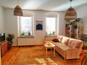 uma sala de estar com um sofá e duas janelas em Apartament Borówka em Jedlina-Zdrój