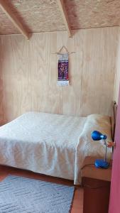 1 dormitorio con 1 cama y 1 lámpara en una mesa en Cabañas Kela, en Bahía Murta