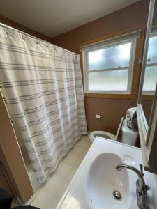 La salle de bains est pourvue d'un lavabo, de toilettes et d'une fenêtre. dans l'établissement Waters Edge Cottage, à Merrimac