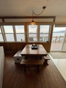 Cette grande chambre dispose d'une table en bois et de fenêtres. dans l'établissement Waters Edge Cottage, à Merrimac
