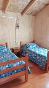 Un dormitorio con 2 camas, una mesa y una falda en Cabañas Kela, en Bahía Murta