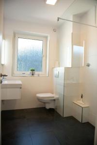 a bathroom with a toilet and a sink and a window at Moderne 2 Zimmer Wohnung (52qm) am CentrO! in Oberhausen