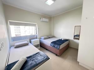 twee bedden in een kleine kamer met een raam bij Sol & Nascente in Guarujá