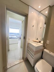 bagno con servizi igienici, lavandino e specchio di Sol & Nascente a Guarujá