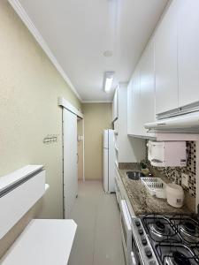 una cucina con armadietti bianchi e piano cottura di Sol & Nascente a Guarujá