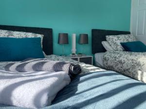 een slaapkamer met 2 bedden en een blauwe achtergrond bij Howard’s House, Home from Home in Thornaby on Tees