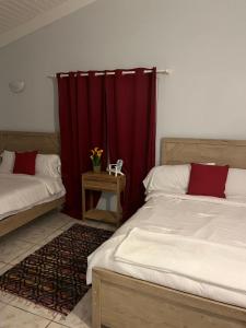 1 dormitorio con 2 camas y cortina roja en La Villas at Pos Chiquito Caribbean Paradise in Aruba, en Savaneta
