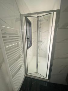 uma cabina de duche ao nível do chão numa casa de banho com uma porta de vidro em Chambre double balcon vue mer em Brest