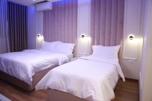2 camas en una habitación de hotel con iluminación púrpura en Sky View Hotel & Restaurant, en Kukës