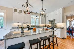 a kitchen with white cabinets and a large island with bar stools at Spacious Salem-Winston Home with Deck! in Winston-Salem