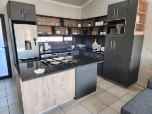 een keuken met zwarte kasten en een fornuis met oven bij Home@Micasa Unit 95 in Potchefstroom