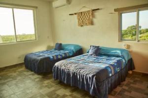 duas camas num quarto com duas janelas em Villa Los Nonos em Mérida