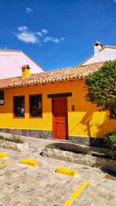 un edificio amarillo con una puerta roja en un aparcamiento en Casa Mostaza Pueblito Boyacense, en Duitama