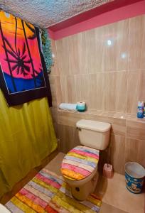 a bathroom with a toilet and a painting on the wall at Cindy's Garden Stay in Ocho Rios