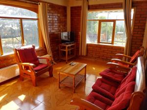 sala de estar con sofá, sillas y TV en Casa Cerro Divisadero, en Coyhaique